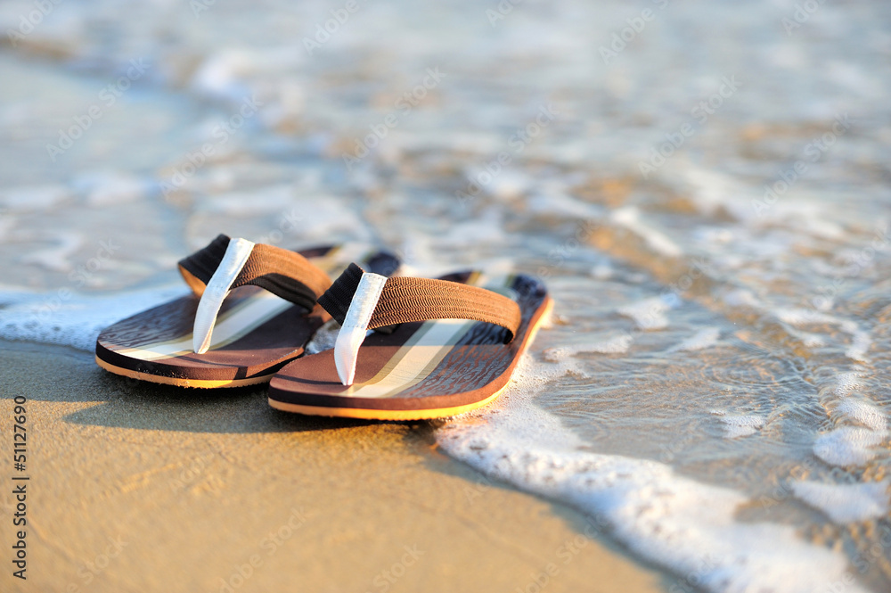 Flip flops on a sandy ocean beach