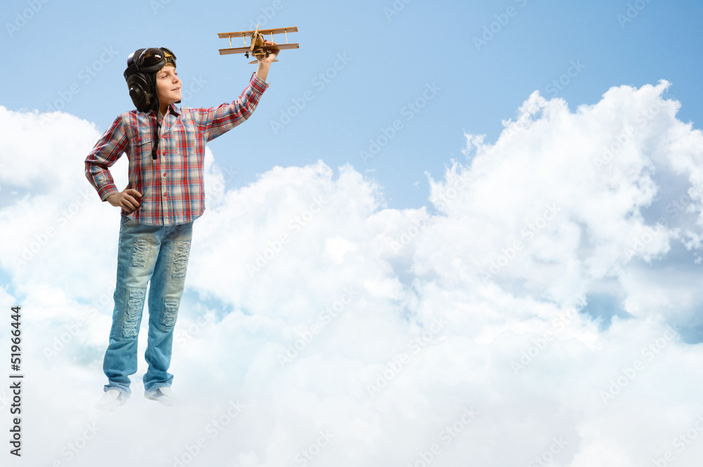 Boy in helmet pilot playing with a toy airplane