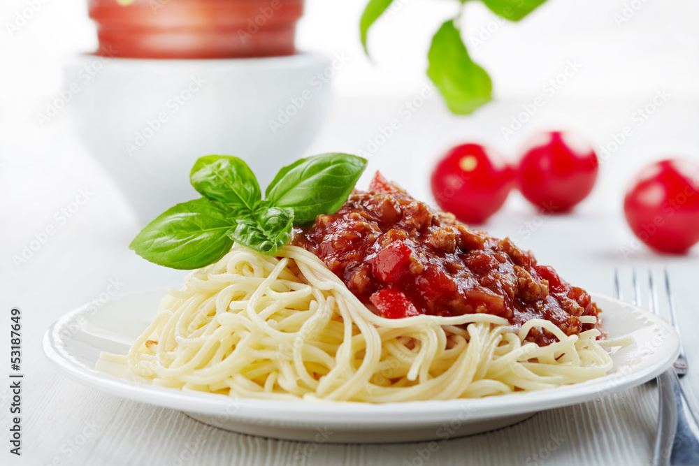 Spaghetti bolognese and green basil leaf on white plate