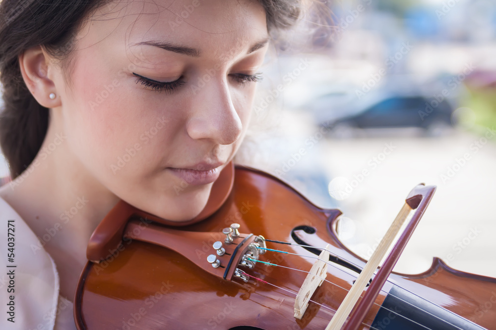 Portrait of a pretty young female playing the violin.