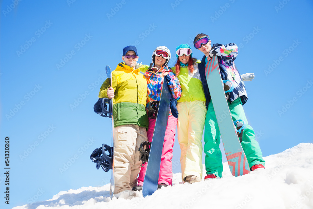 四个快乐的朋友拥抱并抱着滑雪板