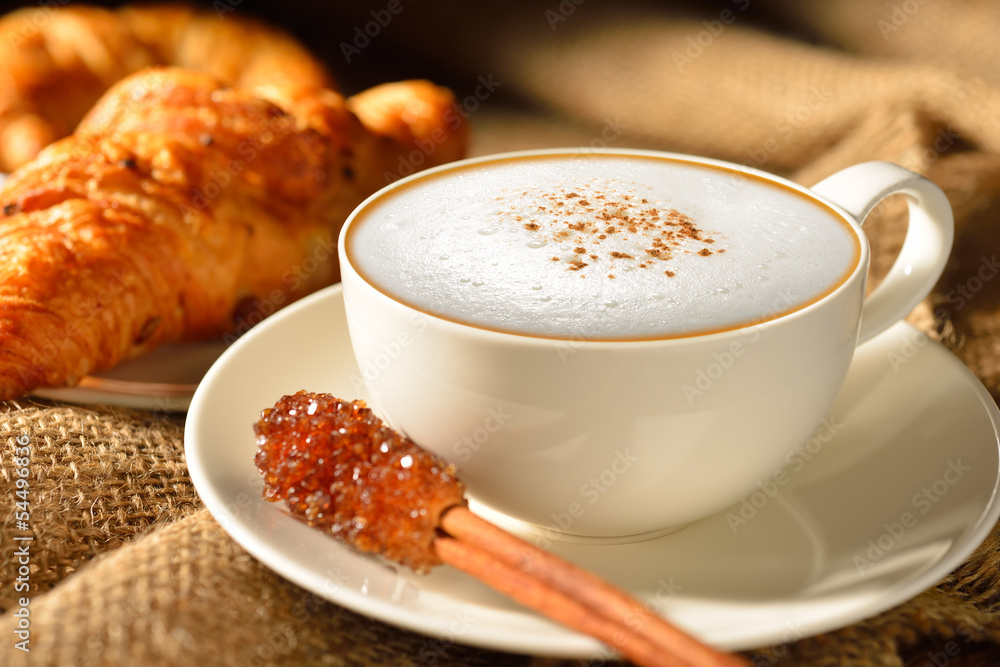 A cup of cappuccino with bread and croissant