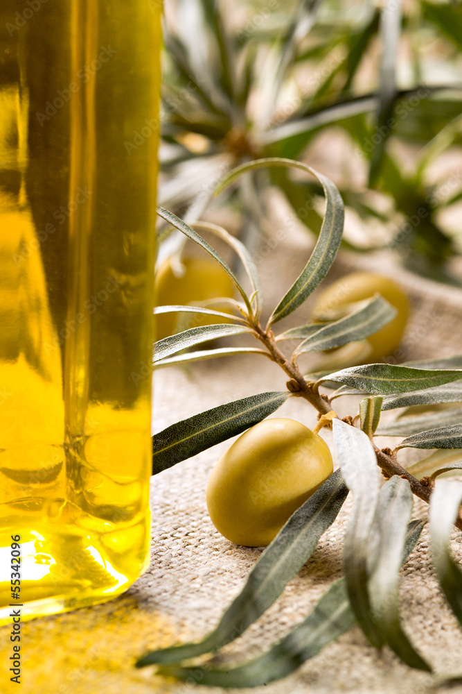 Green olive with bottle of oil on a wooden table