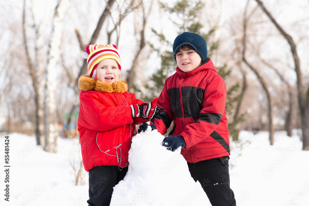 Boy and girl playing with snow in winter park