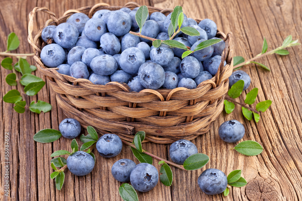 basket with fresh blueberry on wooden background