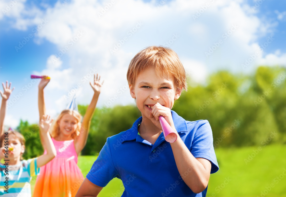 Happy boy blows horn on birthday party