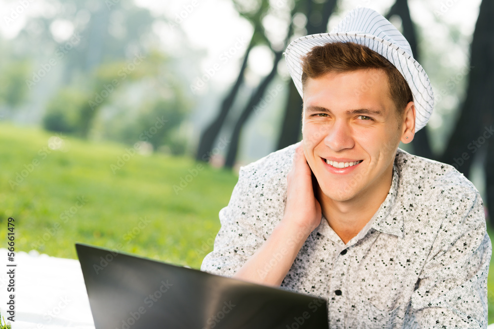 young man working in the park with a laptop