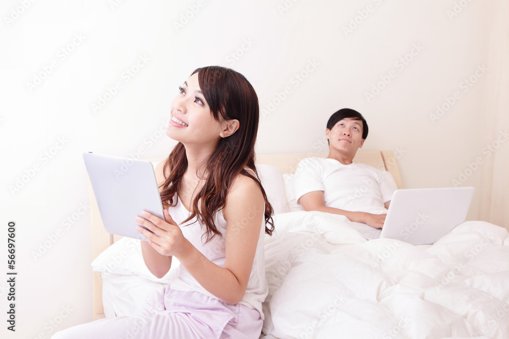 Cheerful couple using touch pad in bed