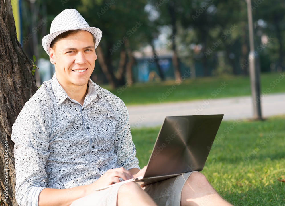 young man working in the park with a laptop