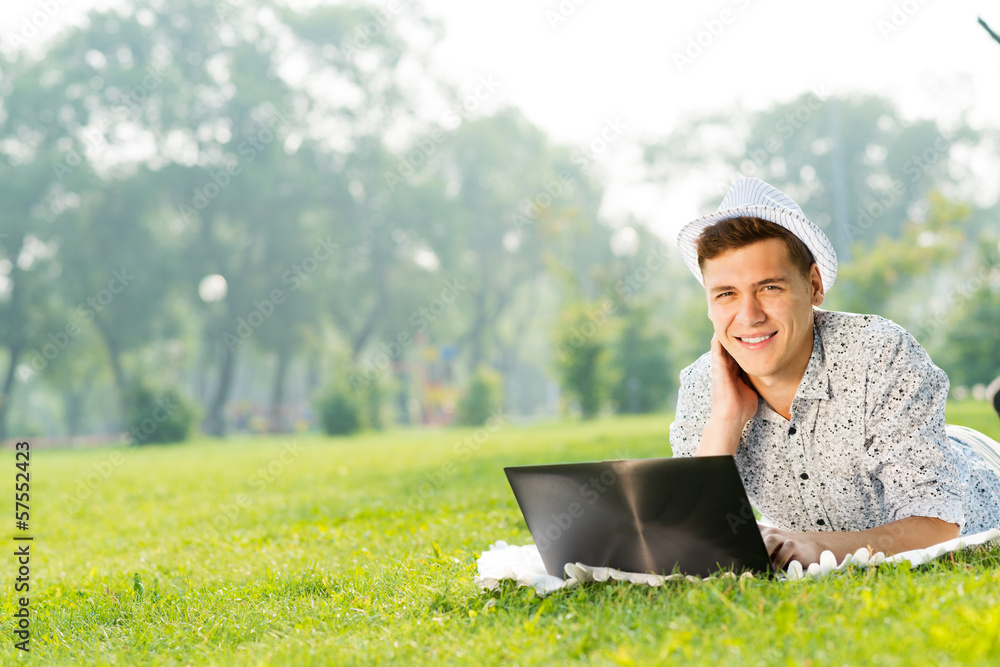 young man working in the park with a laptop