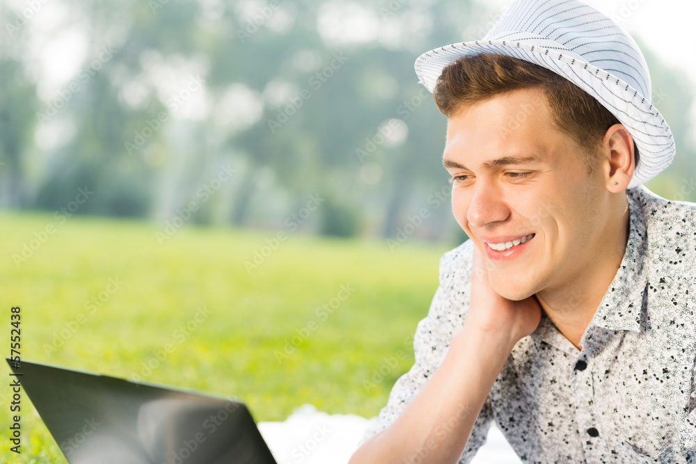 young man working in the park with a laptop