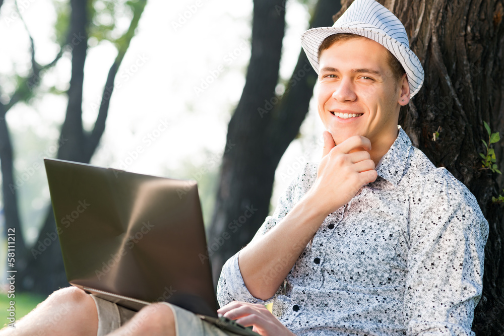 young man working in the park with a laptop