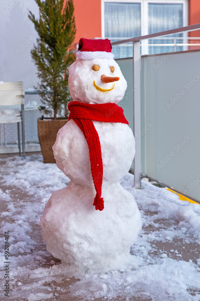 阳台上戴着红帽子和围巾的雪人