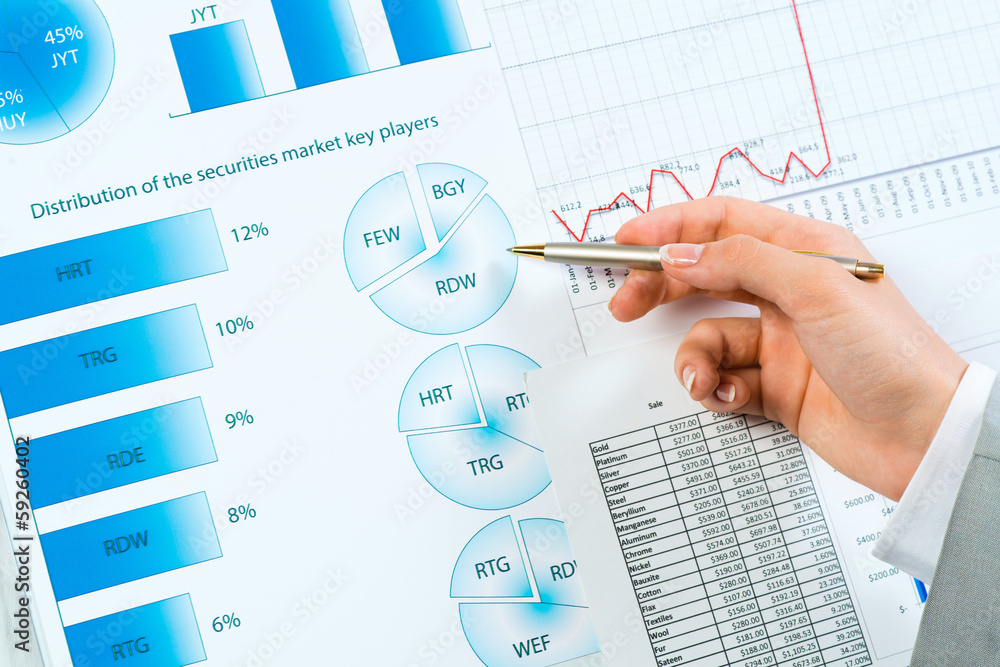 female hand pointing pen on financial charts