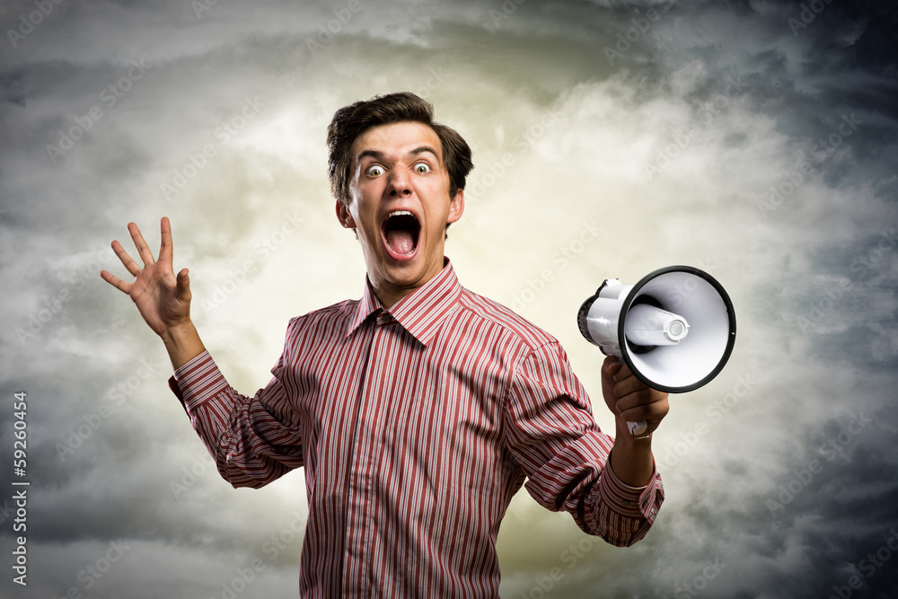 Portrait of a young man shouting using megaphone