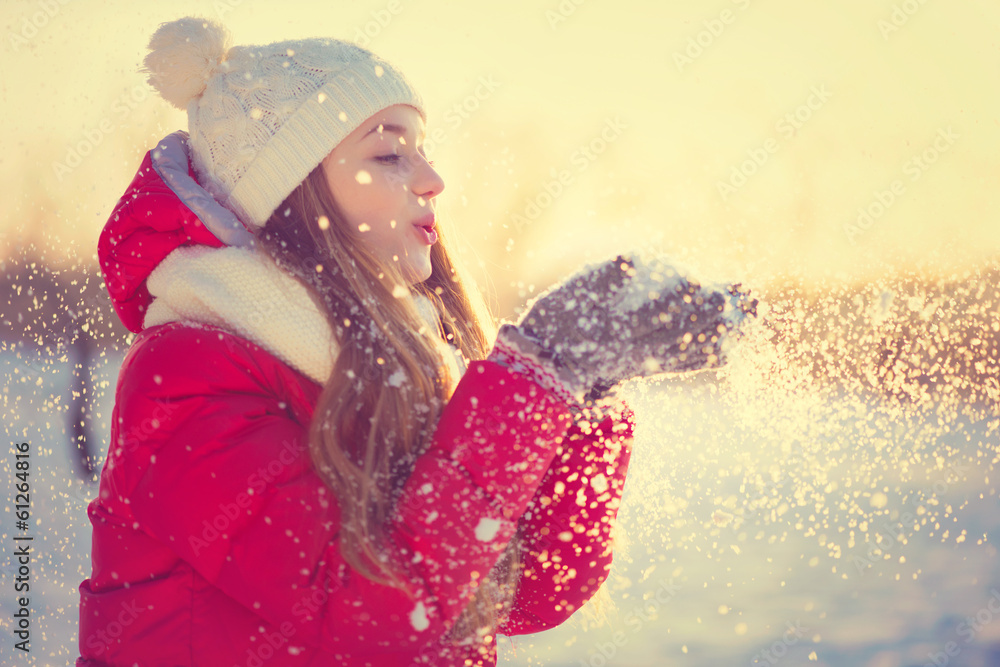 美丽的冬季女孩在霜冻的冬季公园吹雪。户外