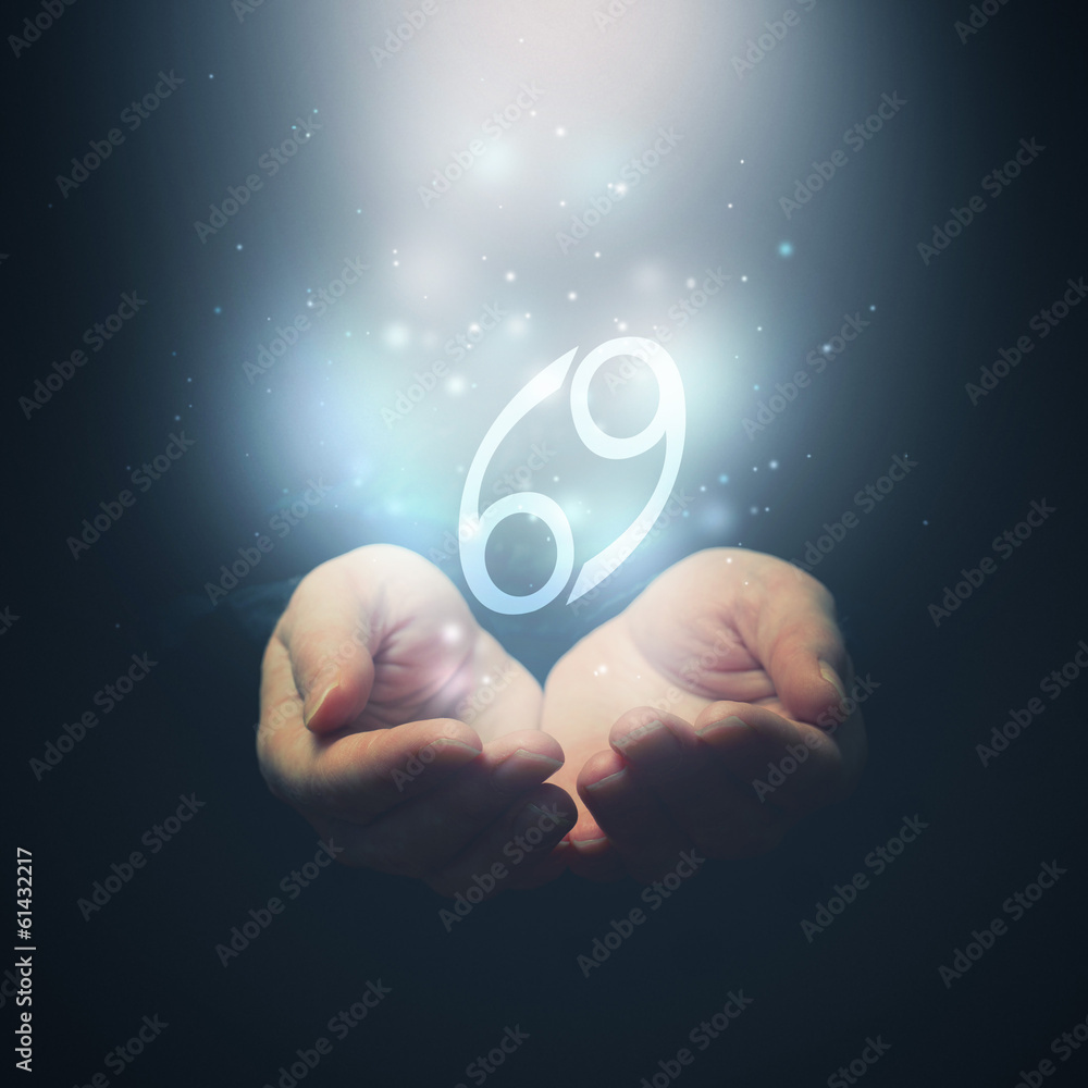 Female hands opening to light and holding zodiac sign for Cancer