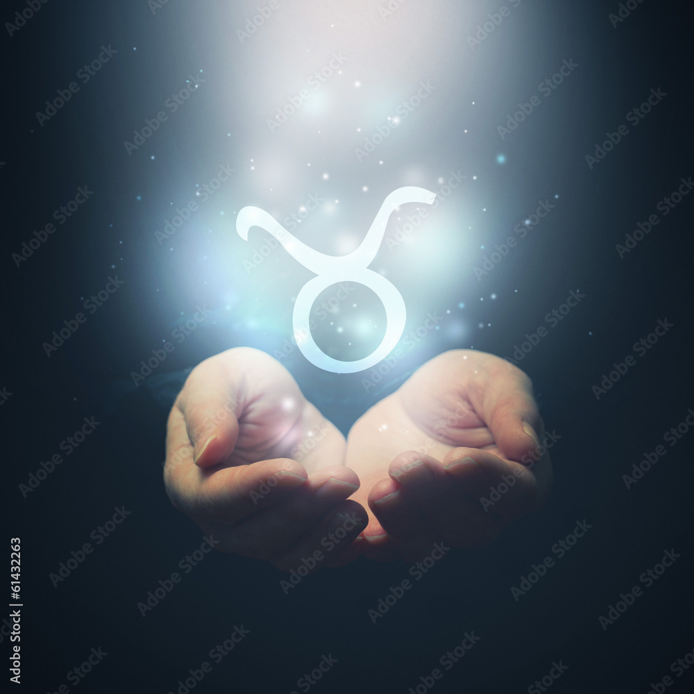 Female hands opening to light and holding zodiac sign for Taurus