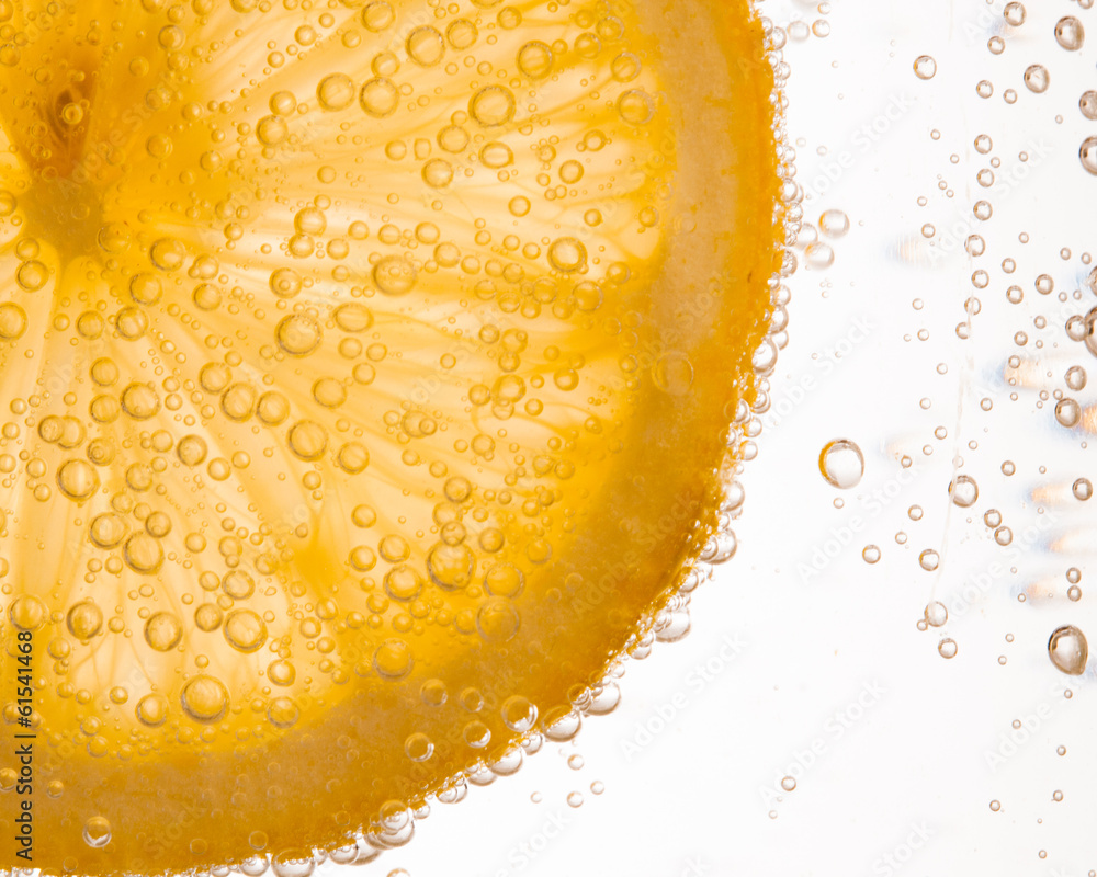 close-up of lemon slice in clear water with bubbles