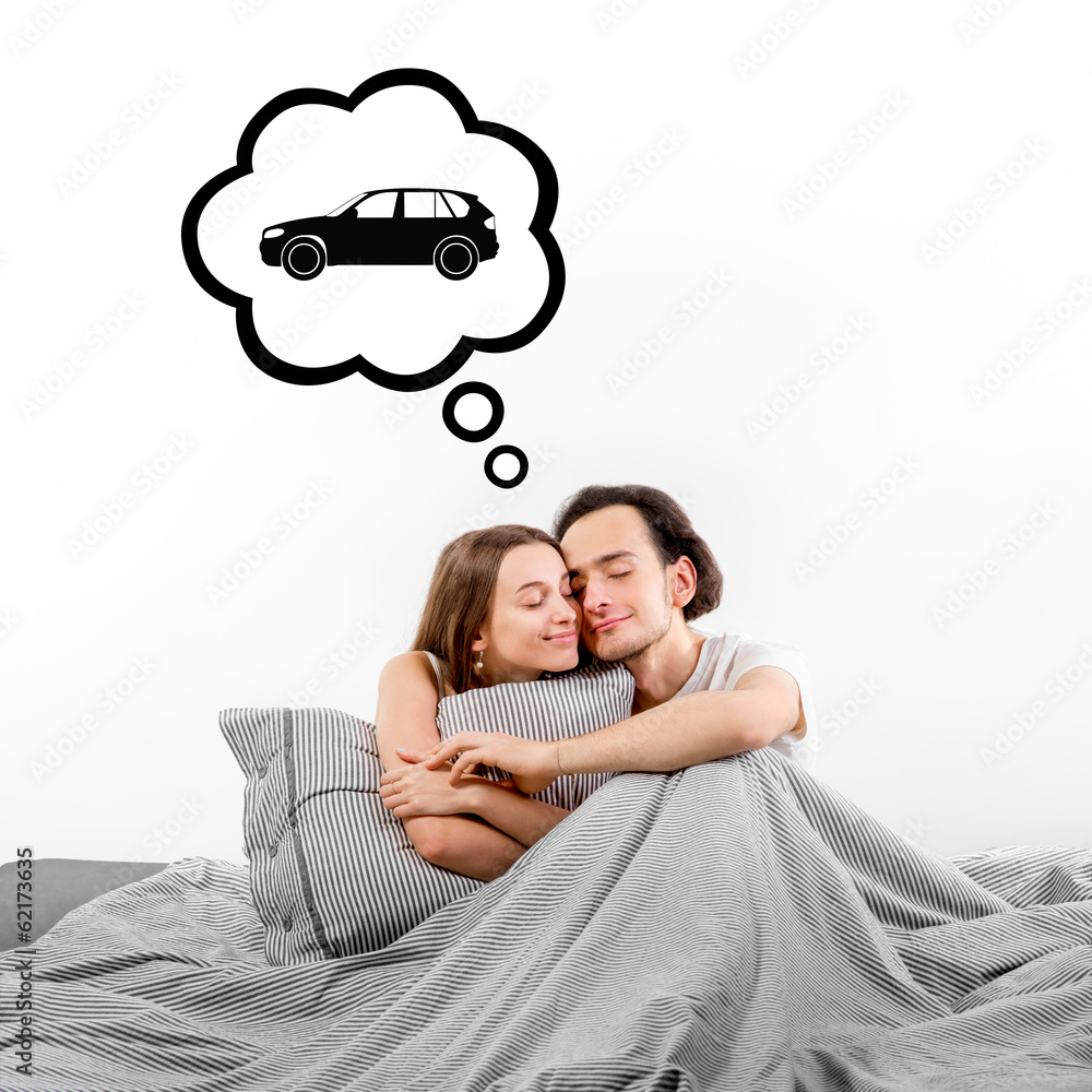 Happy couple in bed thinking and dreaming about car on white bac