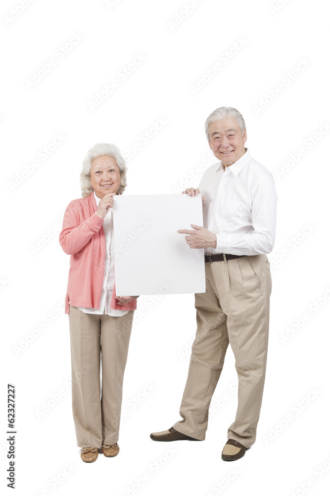 .Senior couple holding white board.