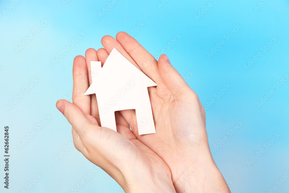 Little paper house in hand close-up, on light background