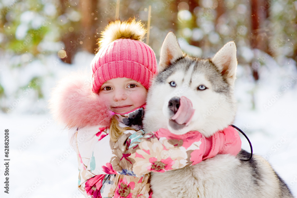 girl hugging Huskies in winter forest