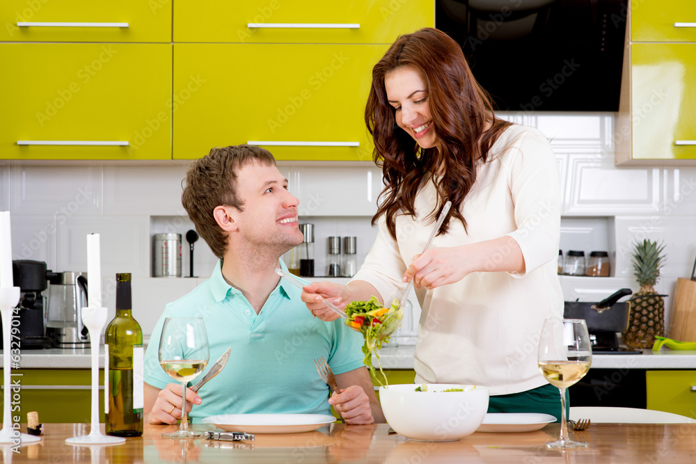 Beautiful couple preparing to the dinner with salad and pasta on