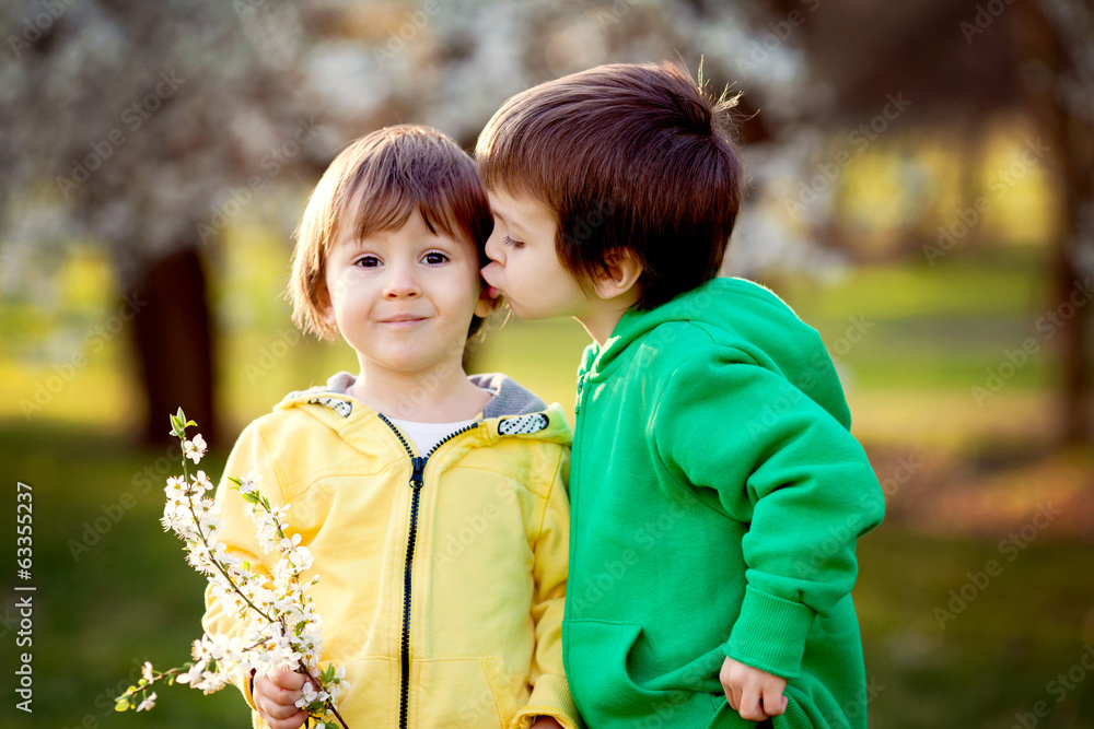 Two little kids in the park, having fun under a blooming tree