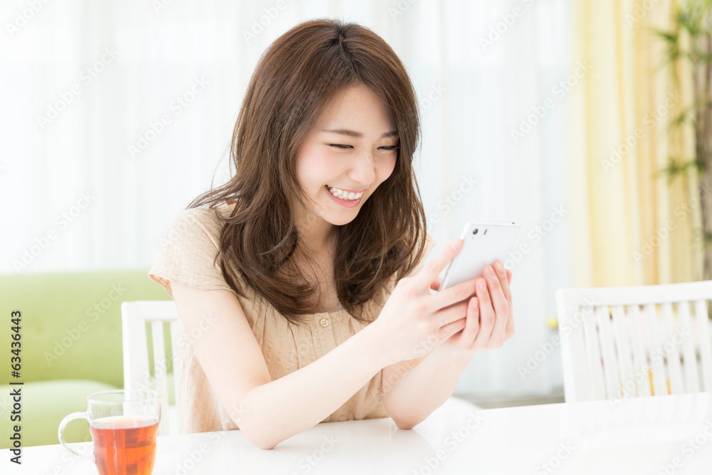 部屋でスマートフォンを見る女性