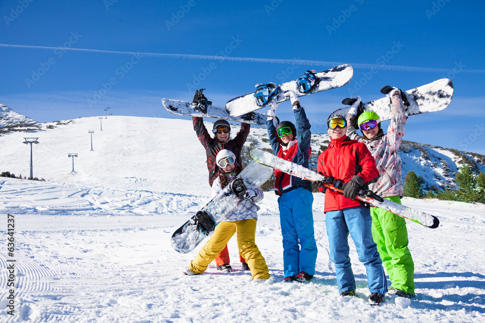 Five snowboarders holding oards and skies together