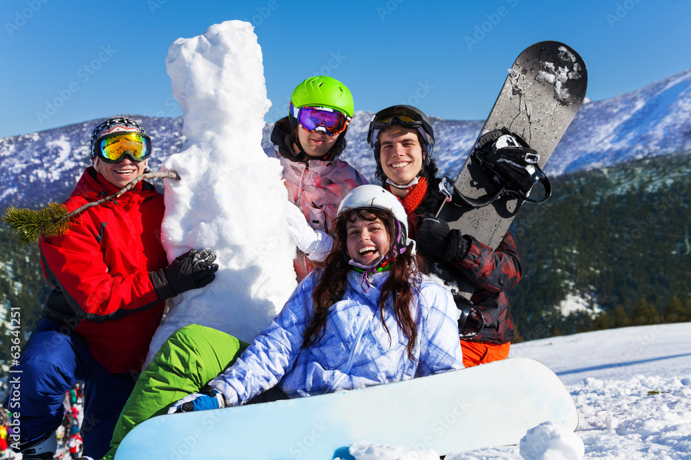 四个年轻人带着滑雪板和雪人