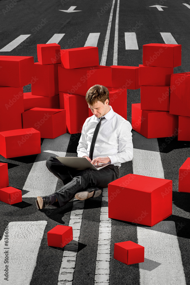 businessman sitting and working with laptop on the asphalt road