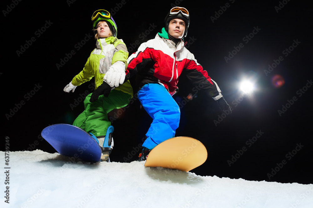 两名单板滑雪运动员准备在夜间滑行