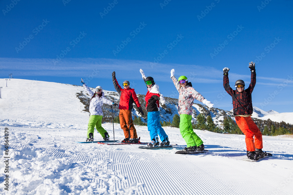 Skier and snowboarders in a row lifting hands up