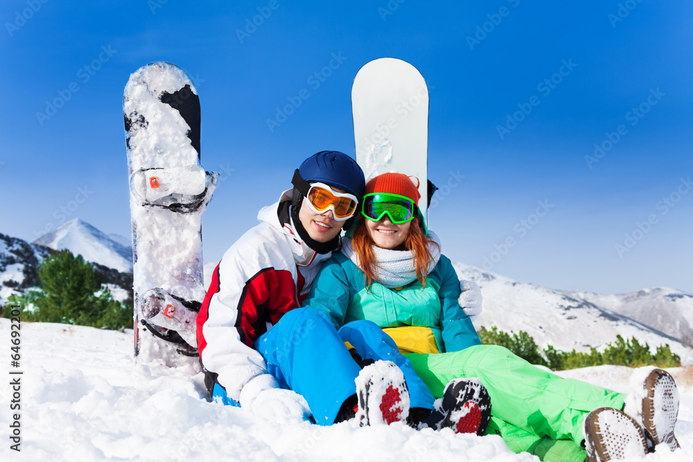 戴着滑雪面罩坐在雪地上的情侣