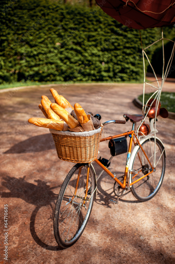 Bicycle with basket full of baguettes standing in the park