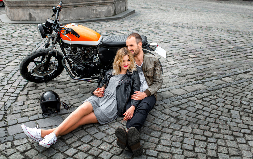 Couple lying on the paving near the motorcycle