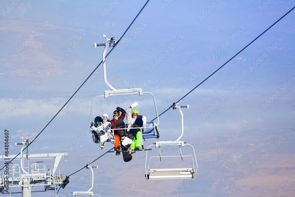 Three snowboarders sitting on ropeway