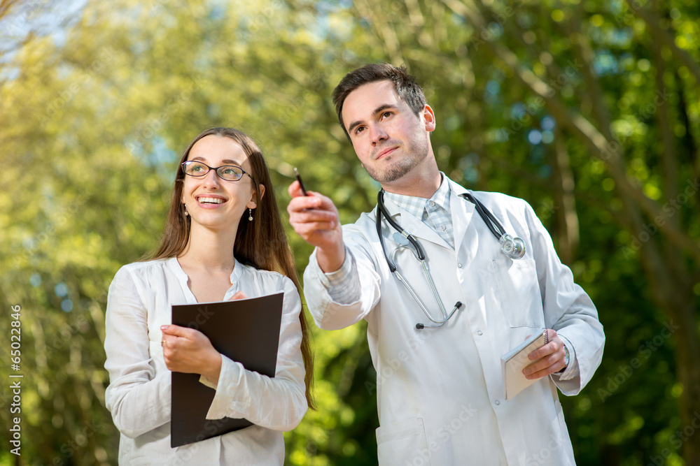 Young doctor with assistant in the park.