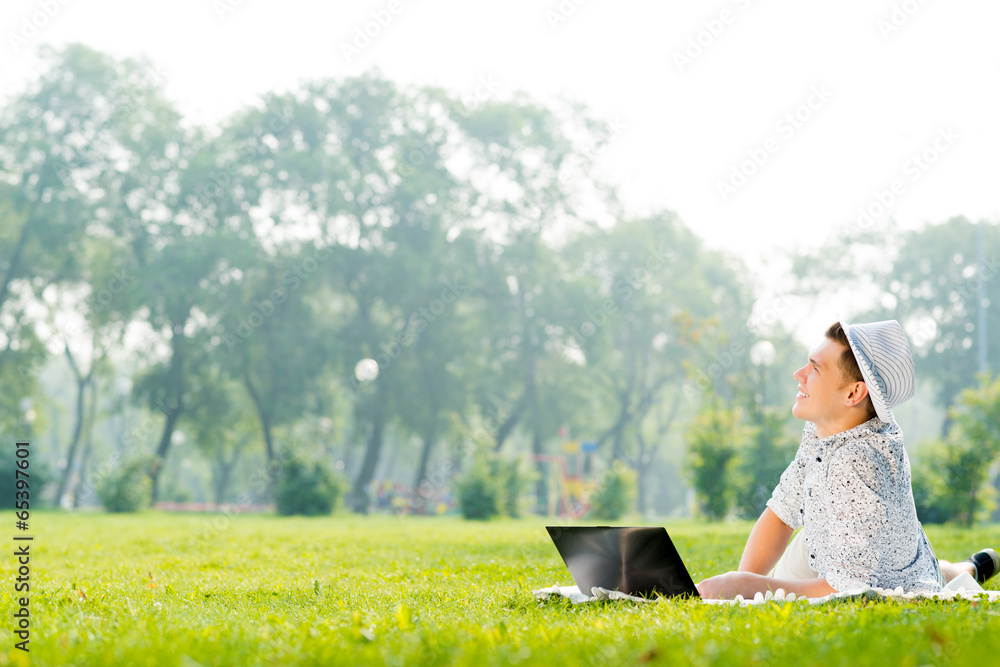 young man working in the park with a laptop