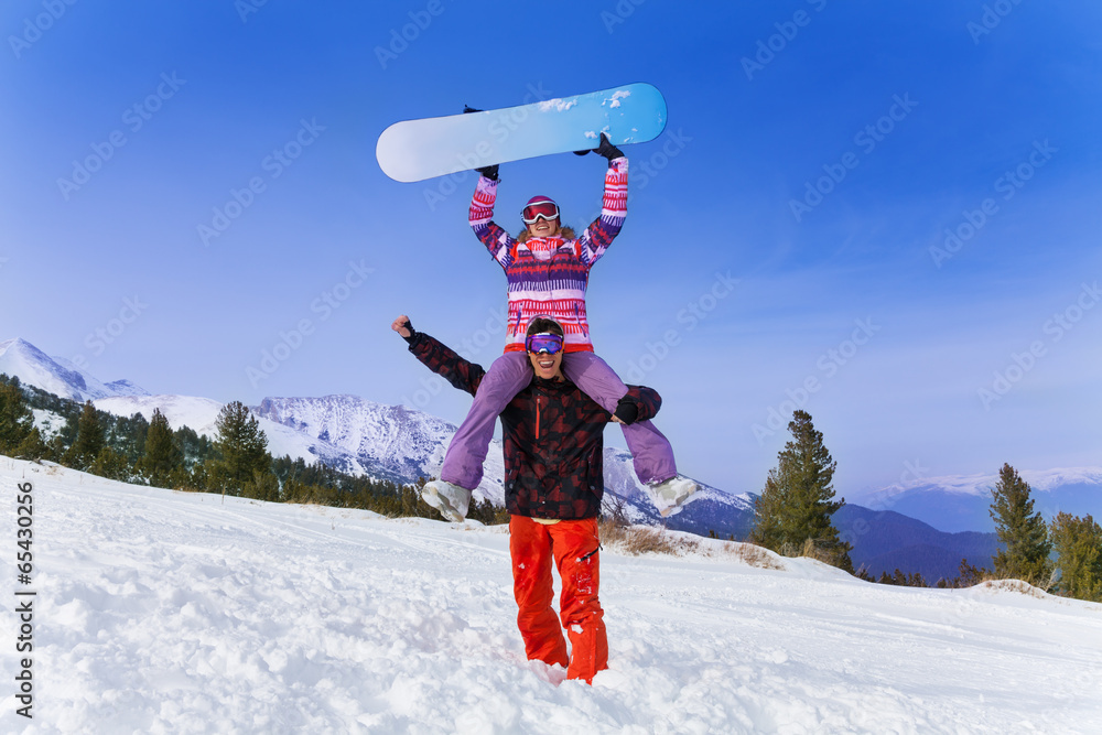 快乐的单板滑雪运动员，肩上扛着女人