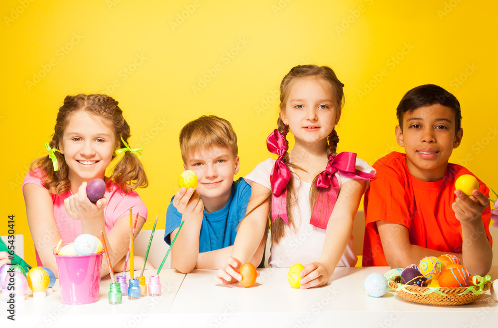 Four children holding Easter eggs at the table