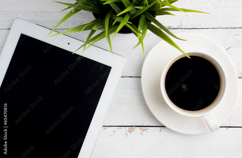 Top view of office desk, a cup of coffee and tablet computer