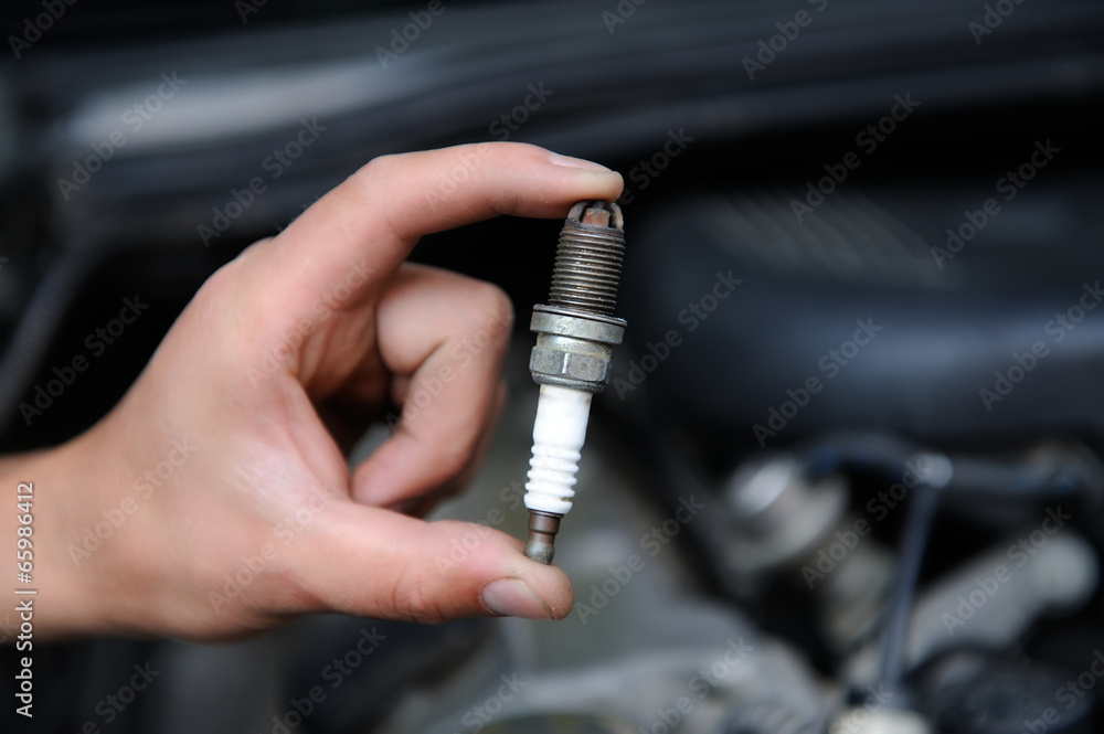 Auto mechanic holds an spark plug