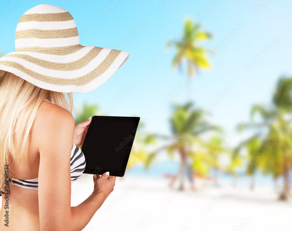 Blond girl with tablet on tropical beach