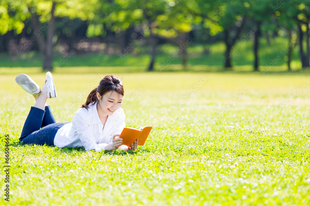 young asian woman reading book in the park