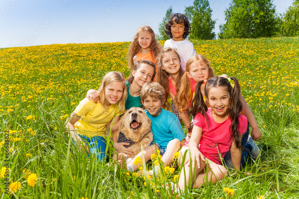 Cheerful kids with dog sitting on the grass