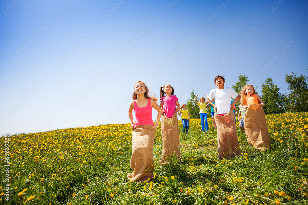 Positive children jump in sacks and playing