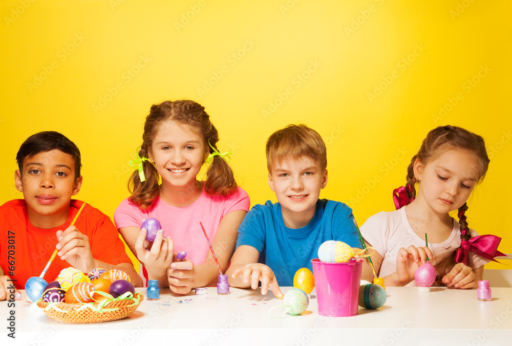 Four children colour Easter eggs at the table